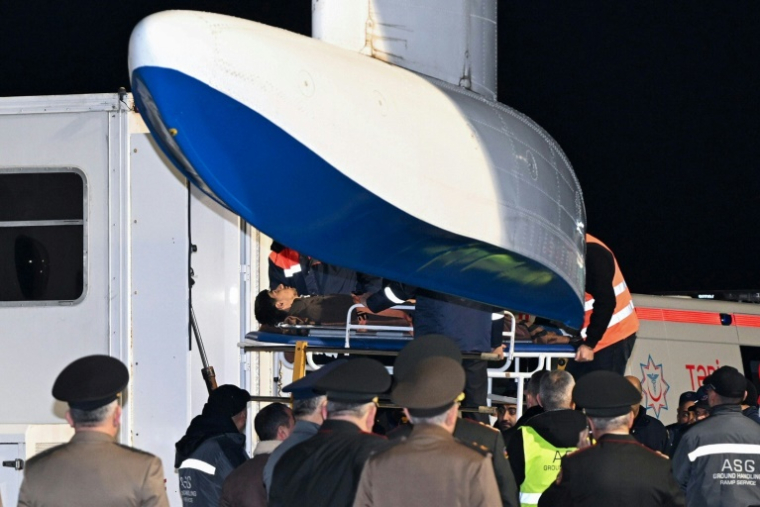 Le personnel au sol et les médecins de l'aéroport international Heydar Aliyev de Bakou assistent les citoyens azerbaïdjanais qui ont survécu au crash de l'avion d'Azerbaijan Airlines à leur arrivée à l'aéroport, le 26 décembre 2024 ( AFP / STRINGER )