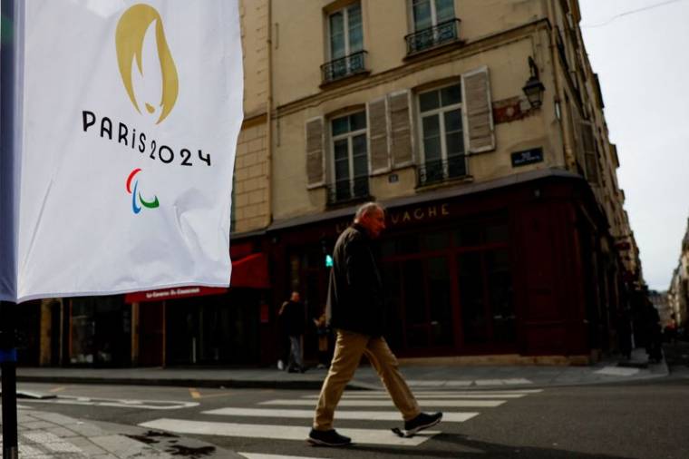 Un homme passe devant un drapeau portant le logo des Jeux olympiques de Paris 2024