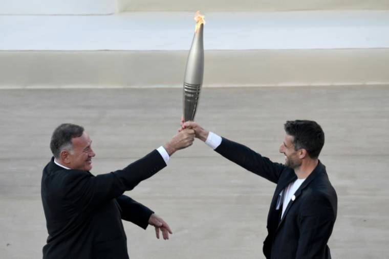 Le président du comité olympique hellénique Spyros Capralos (à gauche) remet la flamme olympique au président du Comité d'organisation des JO-2024 de Paris Tony Estanguet lors d'une cérémonie à Athènes le 26 avril 2024 ( AFP / Angelos Tzortzinis )