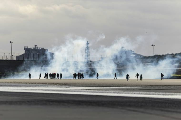 Des migrants candidats à la traversée de la Manche sont aspergés de gaz lacrymogène par la police pour les empêcher de monter à bord d'une embarcation  le 26 avril 2024 à Loon-Plage, dans le Nord ( AFP / Sameer Al-DOUMY )