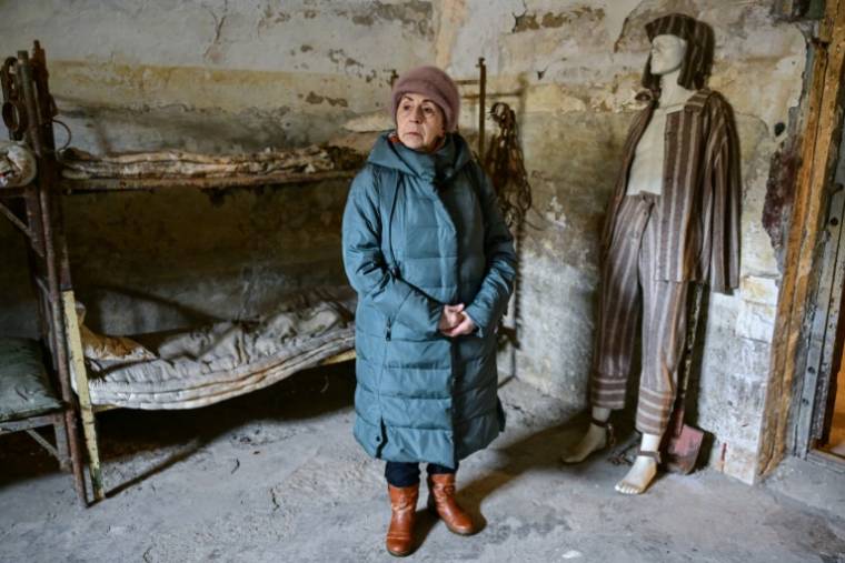Niculina Moica, près d'un mannequin portant des vêtements de détenu, dans une ancienne cellule de la prison de Jilava, le 14 février 2024 en Roumanie ( AFP / Daniel MIHAILESCU )