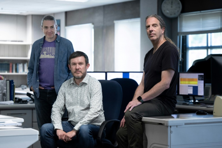 David MacMahon, Steve Croft, et Matt Lebofsky (de gauche à droite), responsables pour le projet Breakthrough Listen Initiative, posent dans la salle de contrôle du radiotélescope de l'observatoire de Green Bank, le 21 mai 2024 en Virginie-Occidentale ( AFP / Brendan Smialowski )