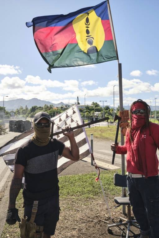 Des indépendantistes tiennent un drapeau kanak et un drapeau breton devant un barrage à Nouméa, en Nouvelle-Calédonie, le 24 mai 2024 ( AFP / Theo Rouby )