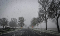 La neige tombe alors que des véhicules circulent sur une route près de Caen, dans le nord-ouest de la France, le 21 novembre 2024 ( AFP / LOU BENOIST )