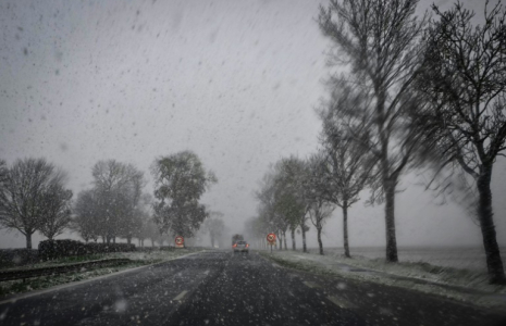 La neige tombe alors que des véhicules circulent sur une route près de Caen, dans le nord-ouest de la France, le 21 novembre 2024 ( AFP / LOU BENOIST )