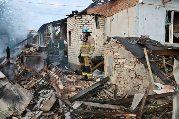 Des pompiers dans les décombres de maisons touchées par une attaque de drones russes dans les environs de Kharkiv, le 21 mai 2024 en Ukraine ( AFP / SERGEY BOBOK )
