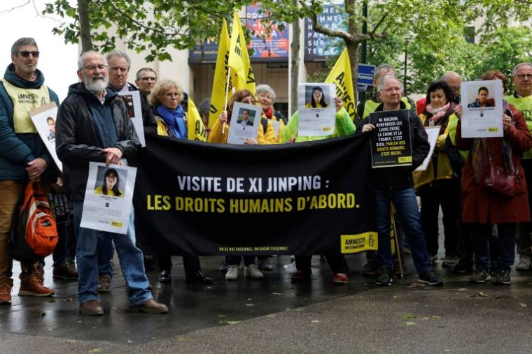 Des militants d'Amnesty International tiennent une banderole "Visite de Xi Jinping : Les droits de l'homme d'abord", lors d'un rassemblement à Paris, le 4 mai 2024 ( AFP / Geoffroy VAN DER HASSELT )