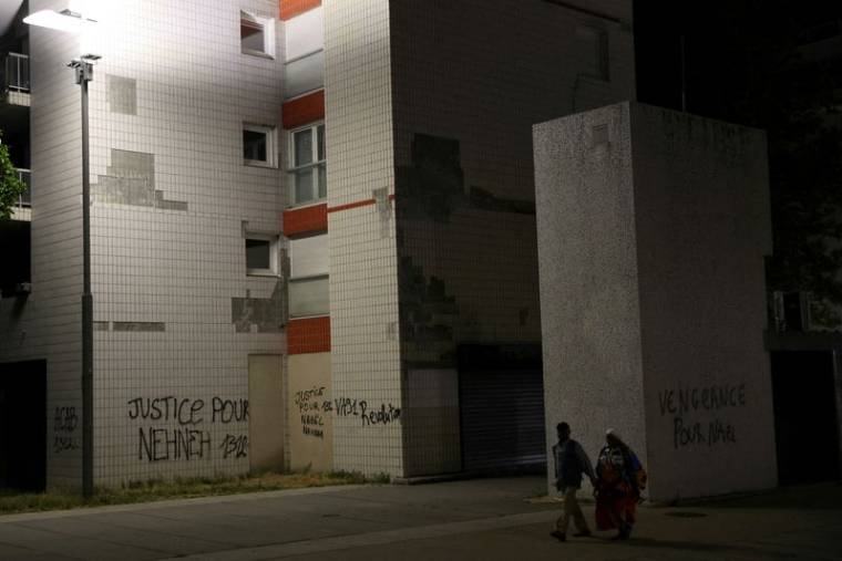 Des habitants passent devant des phrases écrites sur les murs des immeubles de Nanterre, le quartier du jeune de 17 ans tué par un policier lors d'un contrôle routier