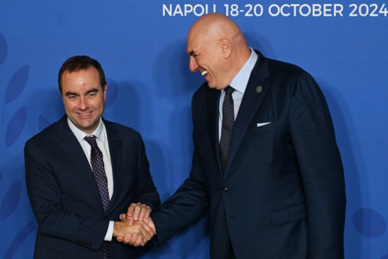 Le ministre italien de la Défense Guido Crosetto (D) et son homologue français Sébastien Lecornu se serrent la main durant la cérémonie d'accueil d'un G7 Défense à Naples le 19 octobre 2024 ( AFP / Tiziana FABI )