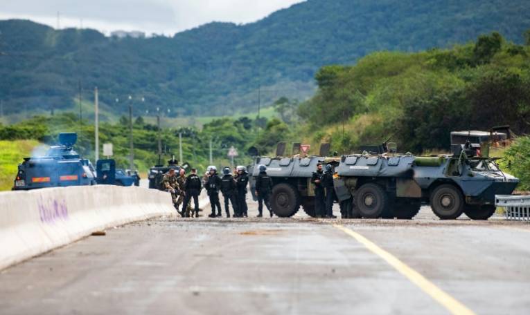 Des gendarmes mobiles sécurisent la zone pendant une opération de nettoyage de la route menant à l'aéroport de Nouméa dans le quartier de Païta, en Nouvelle-Calédonie, le 19 mai 2024 ( AFP / Delphine Mayeur )