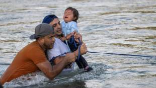 Le migrant vénézuélien Yonder Urbina (c) tient la petite Olga dans ses bras pendant qu'un autre migrant Oskeivys Gonzales les aident à traverser le Rio Grande pour entrer aux Etats-Unis, le 24 septembre 2024 près d'Eagle Pass, au Texas ( AFP / ANDREW CABALLERO-REYNOLDS )