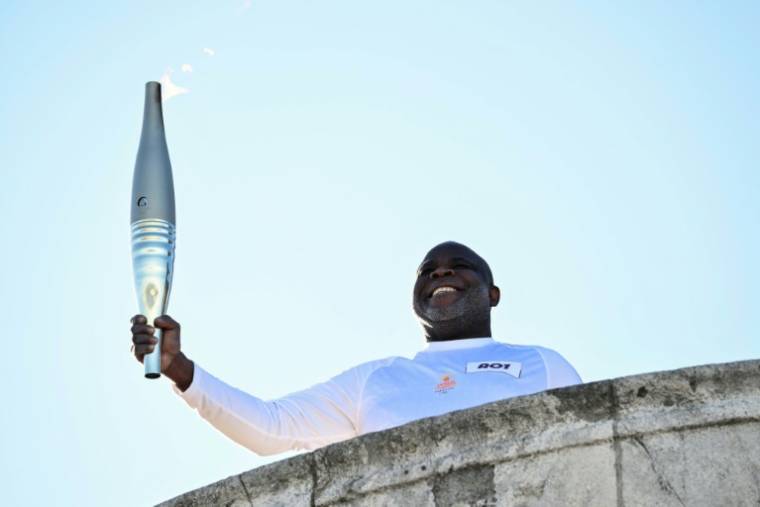 L'ancien footballeur français Basile Boli tient la flamme olympique à la basilique Notre-Dame de la Garde, à Marseille, le 9 mai 2024 ( AFP / CHRISTOPHE SIMON )