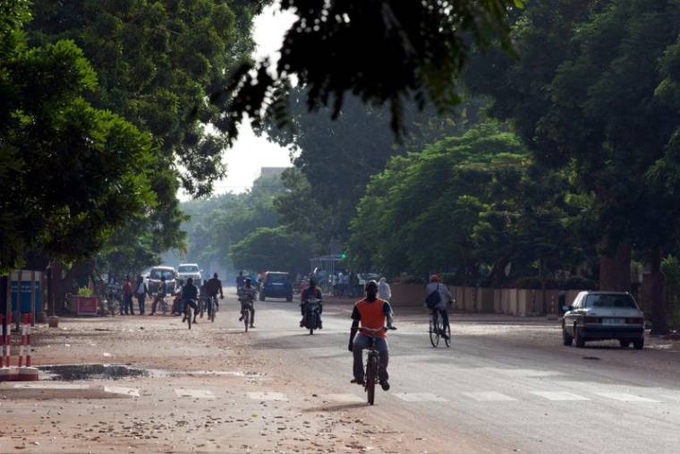 Des personnes se déplacent à vélo et à moto dans une rue de Ouagadougou
