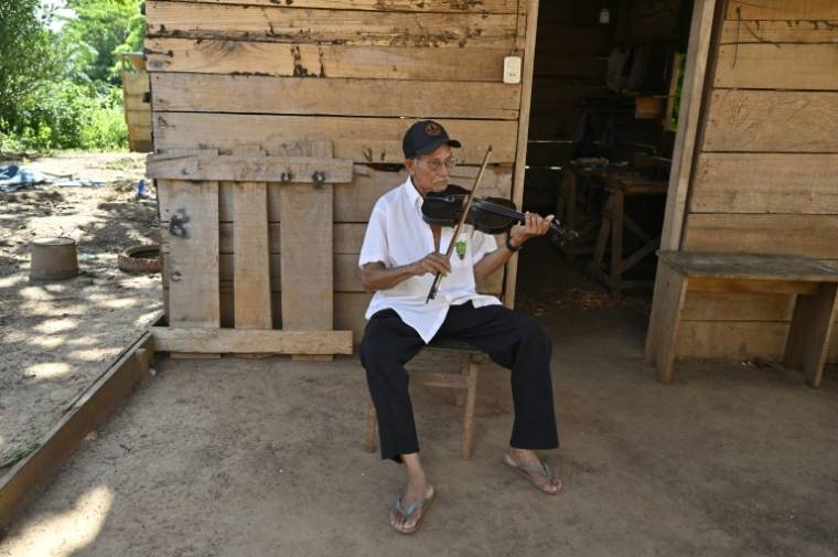 Le luthier Hildeberto Oreyai joue du violon devant son atelier à Urubicha, en Bolivie, le 22 avril 2024  ( AFP / AIZAR RALDES )