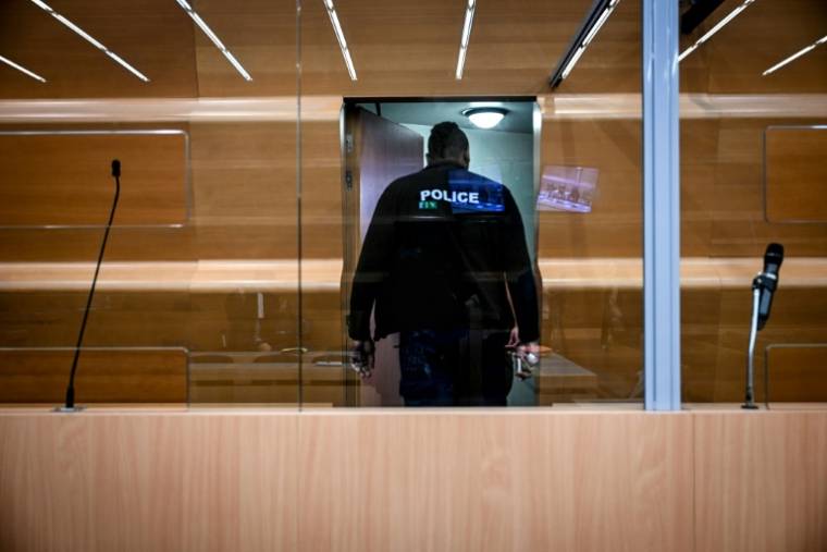 Un policier inspecte le box des accusés dans la salle d'audience du tribunal de Grenoble avant le procès en appel de Gabriel Fortin devant la Cour d'assises de l'Isère, le 13 mai 2024 ( AFP / OLIVIER CHASSIGNOLE )