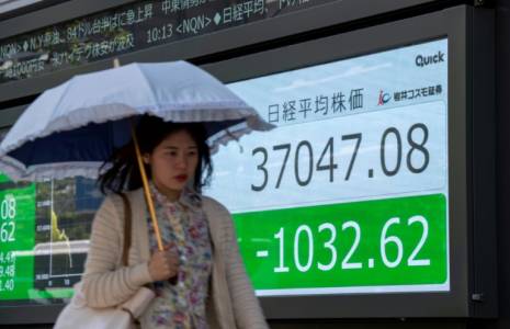 Une femme passe devant un panneau électronique affichant le cours de l'indice Nikkei de la Bourse de Tokyo dans une rue de Tokyo, le 19 avril 2024 ( AFP / Kazuhiro NOGI )