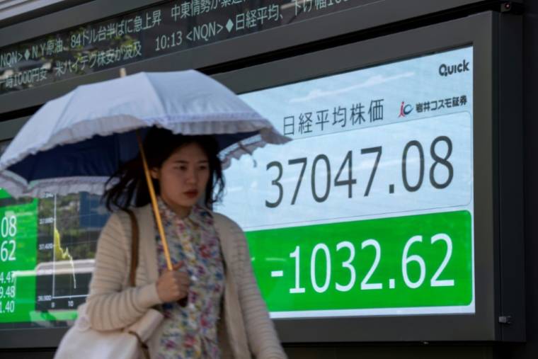 Une femme passe devant un panneau électronique affichant le cours de l'indice Nikkei de la Bourse de Tokyo dans une rue de Tokyo, le 19 avril 2024 ( AFP / Kazuhiro NOGI )
