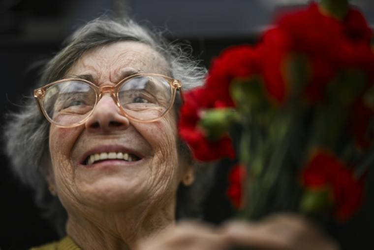 Celeste Caeiro, 90 ans, brandit des oeillets, emblème de la révolution du même nom, lors de la célébration des 50 ans de la chute de la dictature au Portugal, à Lisbonne le 25 avril 2024 ( AFP / PATRICIA DE MELO MOREIRA )