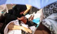 Une femme utilise un ventilateur portatif pour rafraîchir un homme allongé au sol, affecté par la forte chaleur, lors du pèlerinage annuel musulman à Mina près de la Mecque en Arabie saoudite, le 16 juin 2024 ( AFP / FADEL SENNA )
