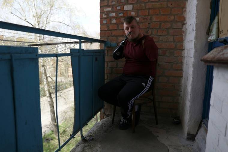 Le sergent ukrainien Valeriï Koutcherenko fume une cigarette à l'aide d'une prothèse mécanique avec des crochets, sur le balcon de son appartement à Bila Tserkva, au sud de Kiev, le 4 avril 2024 ( AFP / Anatolii STEPANOV )