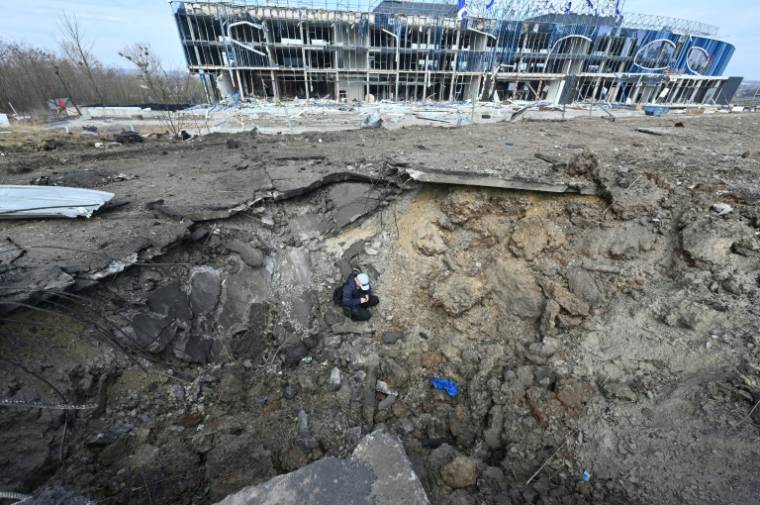 Le cratère laissé par une frappe de missiles russes devant un centre commercial détruit à Kharkiv, est de l'Ukraine, le 6 avril 2024 ( AFP / SERGEY BOBOK )