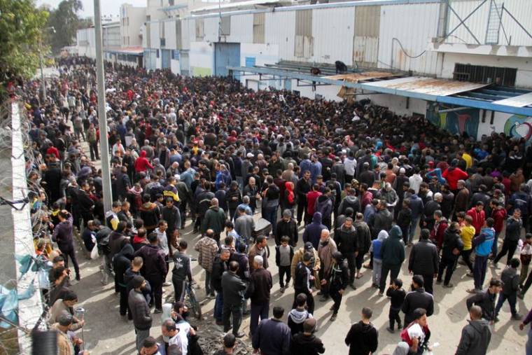 Des Palestiniens se rassemblent pour recevoir de l'aide devant un entrepôt de l'UNRWA dans la ville de Gaza