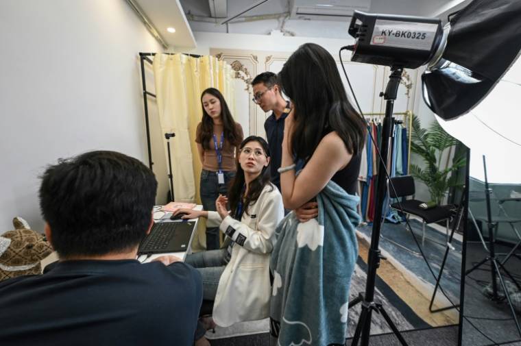 La formatrice Wang Yaxuan (c) échange avec ses étudiants après un live sur TikTok, le 2 avril 2024 à Guangzhou, en Chine ( AFP / Jade GAO )