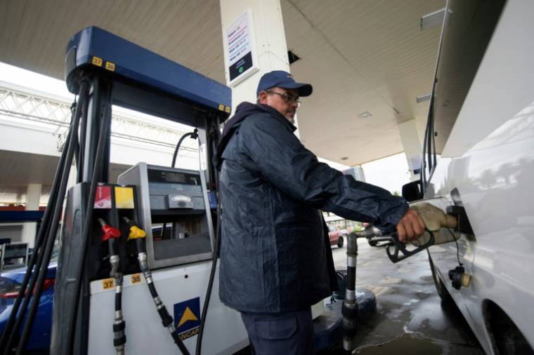 Un employé sert de l'essence dans une station-service de l'entreprise publique ANCAP, le 22 avril 2024 à Montevideo, en Uruguay ( AFP / Pablo VERA )
