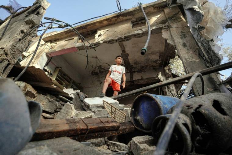 Un jeune Palestinien se tient sur les décombres d'une maison détruite à Nousseirat dans le centre de la bande de Gaza, le 23 mai 2024 ( AFP / Bashar TALEB )