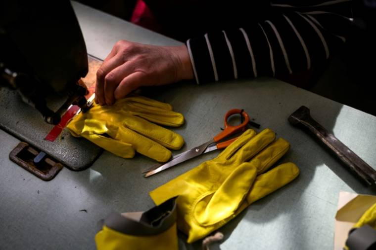 Une employée travaille sur une paire de gants dans l'atelier de La Maison Fabre à Millau, le 15 mars 2024 dans l'Aveyron ( AFP / Lionel BONAVENTURE )