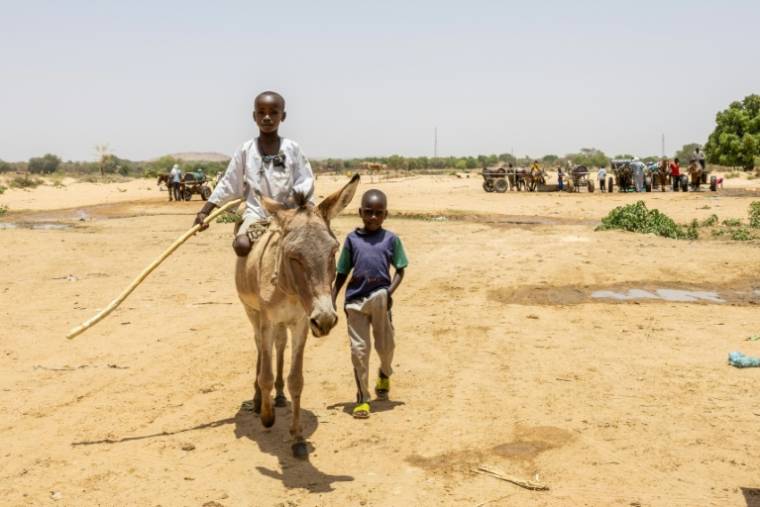 Deux jeunes traversent la frontière entre le Tchad et le Soudan dans le camp de réfugiés de Koufroun, le 9 avril 2024 ( AFP / Joris Bolomey )