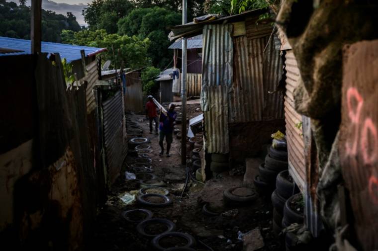 Un habitant transporte des matériaux dans le bidonville "Talus 2", dans le nord de Mayotte, promis à une démolition imminente, le 21 mai 2023 ( AFP / Philippe LOPEZ )