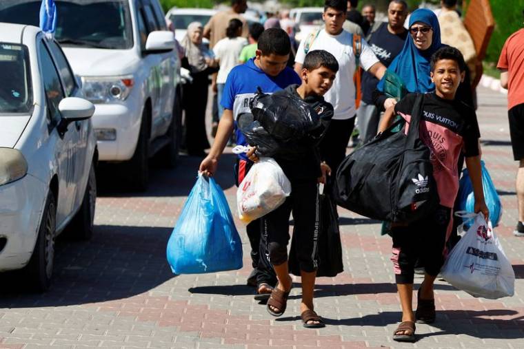 Photo des familles de membres du personnel d'organisations internationales transportent leurs affaires pour se réfugier dans un centre des Nations Unies après que l'UNRWA a annoncé avoir transféré son centre d'opérations central au sud de la bande de Gaza