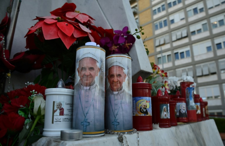 Le portrait du pape François sur des bougies déposées au pied de la statue de Jean-Paul II devant l'hôpital Gemelli à Rome, le 22 février 2025 ( AFP / Isabella BONOTTO )