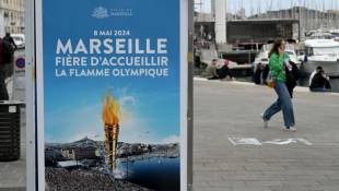 Une affiche "Marseille est fière d'accueillir la flamme olympique" sur le Vieux-Port, le 6 mai 2024 à Marseille ( AFP / Nicolas TUCAT )