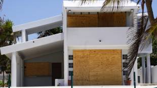 Les portes et fenêtres d'une maison protégées par des panneaux en bois avant l'arrivée de l'ouragan Béryl, le 3 juillet 2024 à Cancun, au Mexique ( AFP / Elizabeth Ruiz )