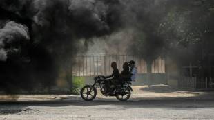 Une moto passe près de pneus en feu lors d'une manifestation contre l'insécurité à Port-au-Prince, en Haïti, le 14 août 2023 ( AFP / Richard PIERRIN  )