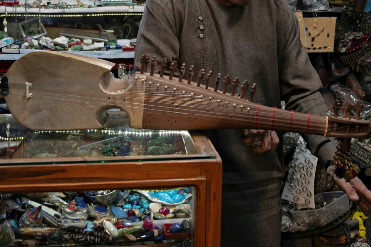 Gull Agha, un joueur amateur afghan de rubab, présente l'instrument dans un magasin à Herat, le 21 décembre 2024 ( AFP / Wakil KOHSAR )