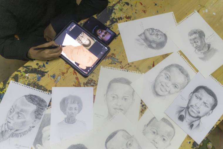 Un artiste du collectif "Art for Memories" dessine les portraits de victimes du génocide rwandais à partir de photos, le 2 avril 2024 à Kigali ( AFP / Guillem Sartorio )