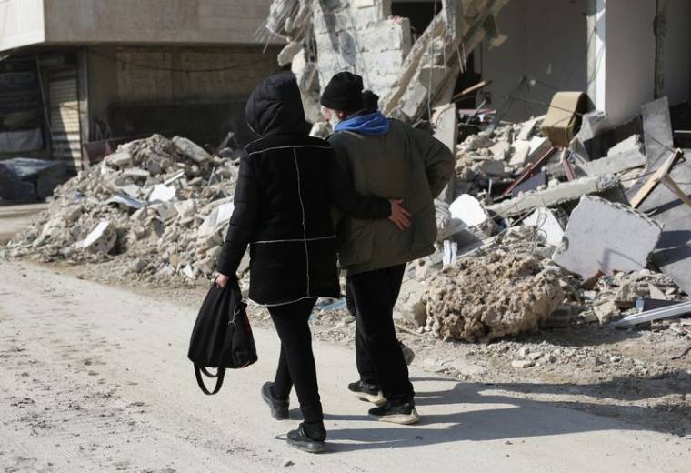 Des gens marchent près des bâtiments endommagés par un tremblement de terre à Jableh, en Syrie