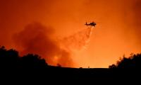 Un hélicoptère largue sa cargaison d'eau sur le feu qui ravage Los Angeles, le 10 janvier 2025 ( AFP / Patrick T. Fallon )