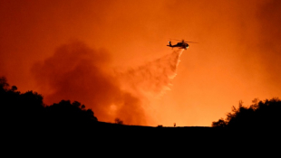 Un hélicoptère largue sa cargaison d'eau sur le feu qui ravage Los Angeles, le 10 janvier 2025 ( AFP / Patrick T. Fallon )