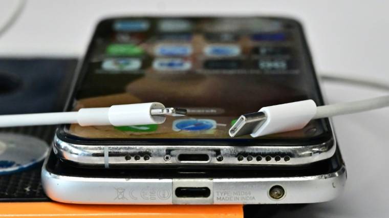 Un chargeur USB-C (d) et un chargeur Lightning d'Apple (g) sur un iPhone et un smartphone Androide superposés, le 11 septembre 2023 à Los Angeles ( AFP / Frederic J. BROWN )