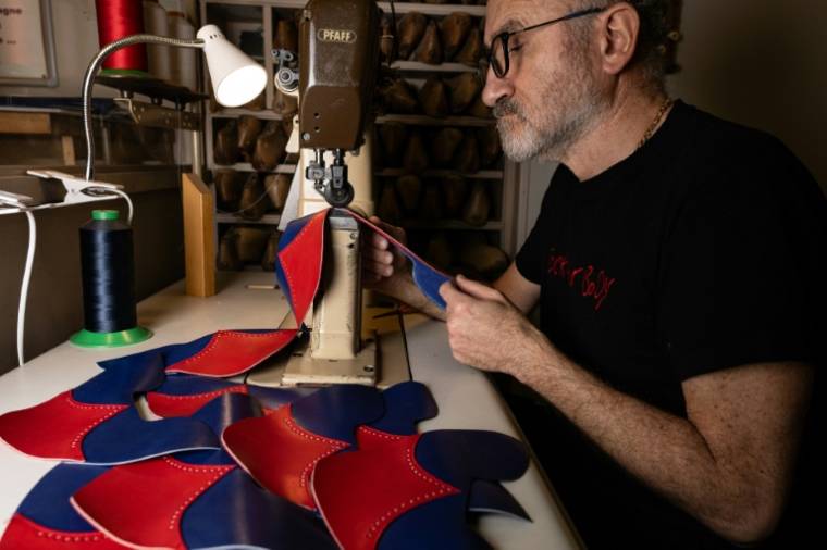 Un bottier prépare des pièces de cuir pour les bottes utilisées par les danseurs du cabaret musical du Moulin Rouge à l'atelier de la maison Clairvoy à Paris, le 12 mars 2024 ( AFP / Miguel MEDINA )