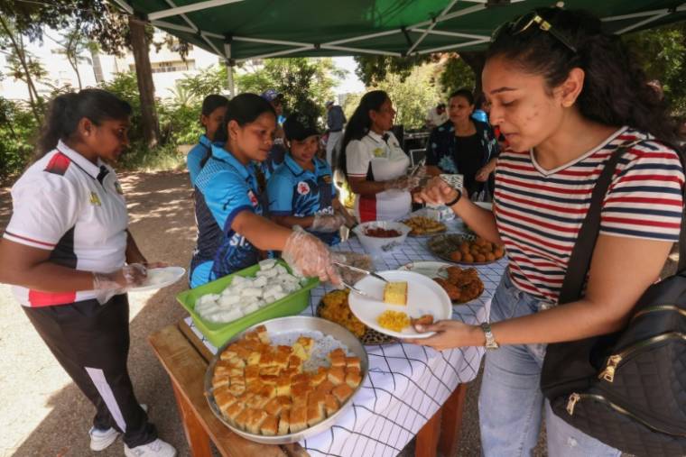 Des immigrés asiatiques partagent un repas lors d'un match de cricket organisé sur un parking à Beyrouth, le 19 mai 2024 ( AFP / ANWAR AMRO )
