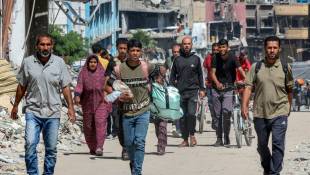 Des Palestiniens marchent le 14 mai 2024, au milieu de bâtiments détruits, dans une rue de Jabaliya, dans le nord de la bande de Gaza, où une guerre oppose Israël au mouvement islamiste palestinien Hamas ( AFP / - )
