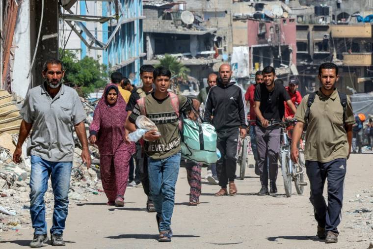 Des Palestiniens marchent le 14 mai 2024, au milieu de bâtiments détruits, dans une rue de Jabaliya, dans le nord de la bande de Gaza, où une guerre oppose Israël au mouvement islamiste palestinien Hamas ( AFP / - )