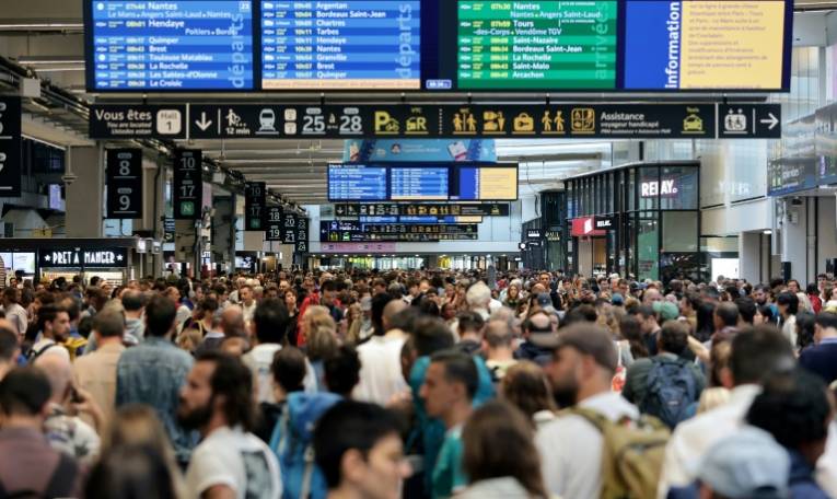 Des passagers se pressent devant les écrans d’information gare Montparnasse à Paris le 26 juillet 2024, après l’annonce d’actes de sabotage sur le réseau TGV  ( AFP / Thibaud MORITZ )