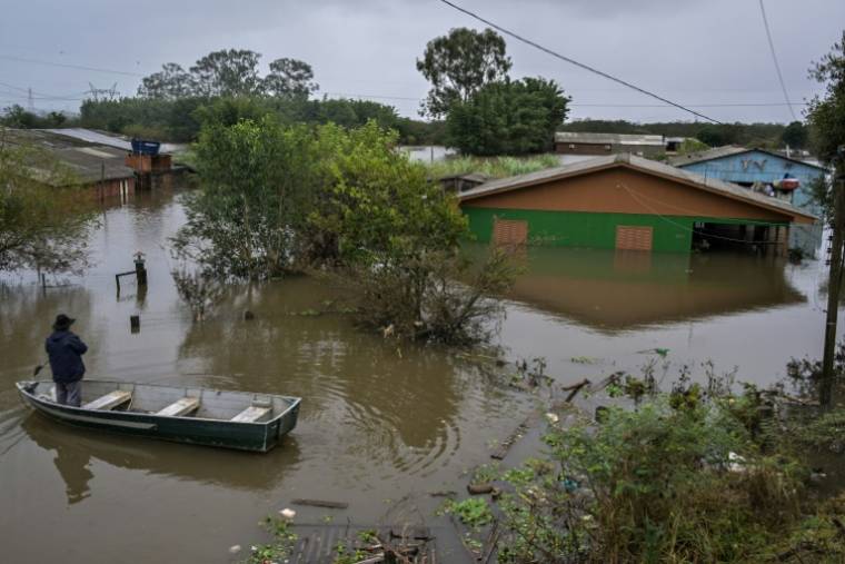 Un homme dans une barque se tient devant une maison inondée à Canoas, dans le sud du Brésil, le 13 mai 2024 ( AFP / Nelson ALMEIDA )
