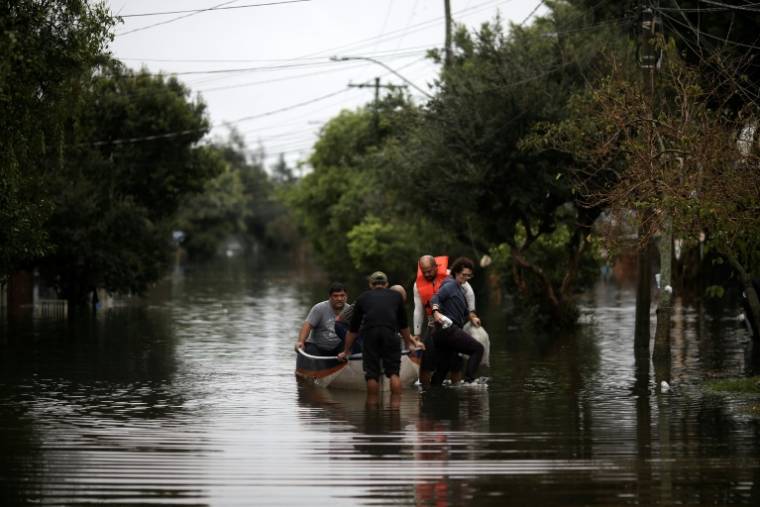 Des personnes empruntent un bateau pour traverser une rue inondée à Porto Alegre, dans l'Etat du Rio Grande do Sul, au Brésil, le 12 mai 2024 ( AFP / Anselmo CUNHA )
